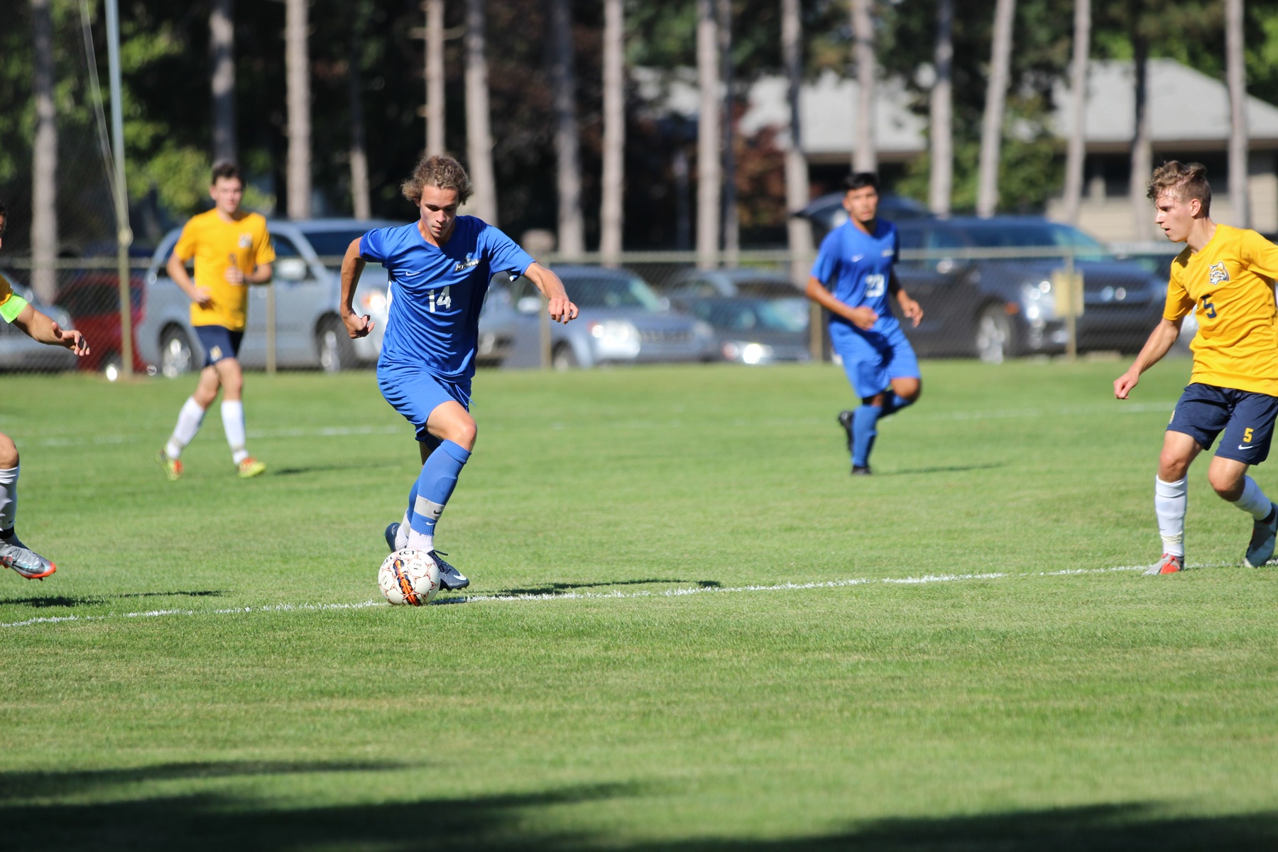Muskegon CC men's soccer player advances the ball up the field.