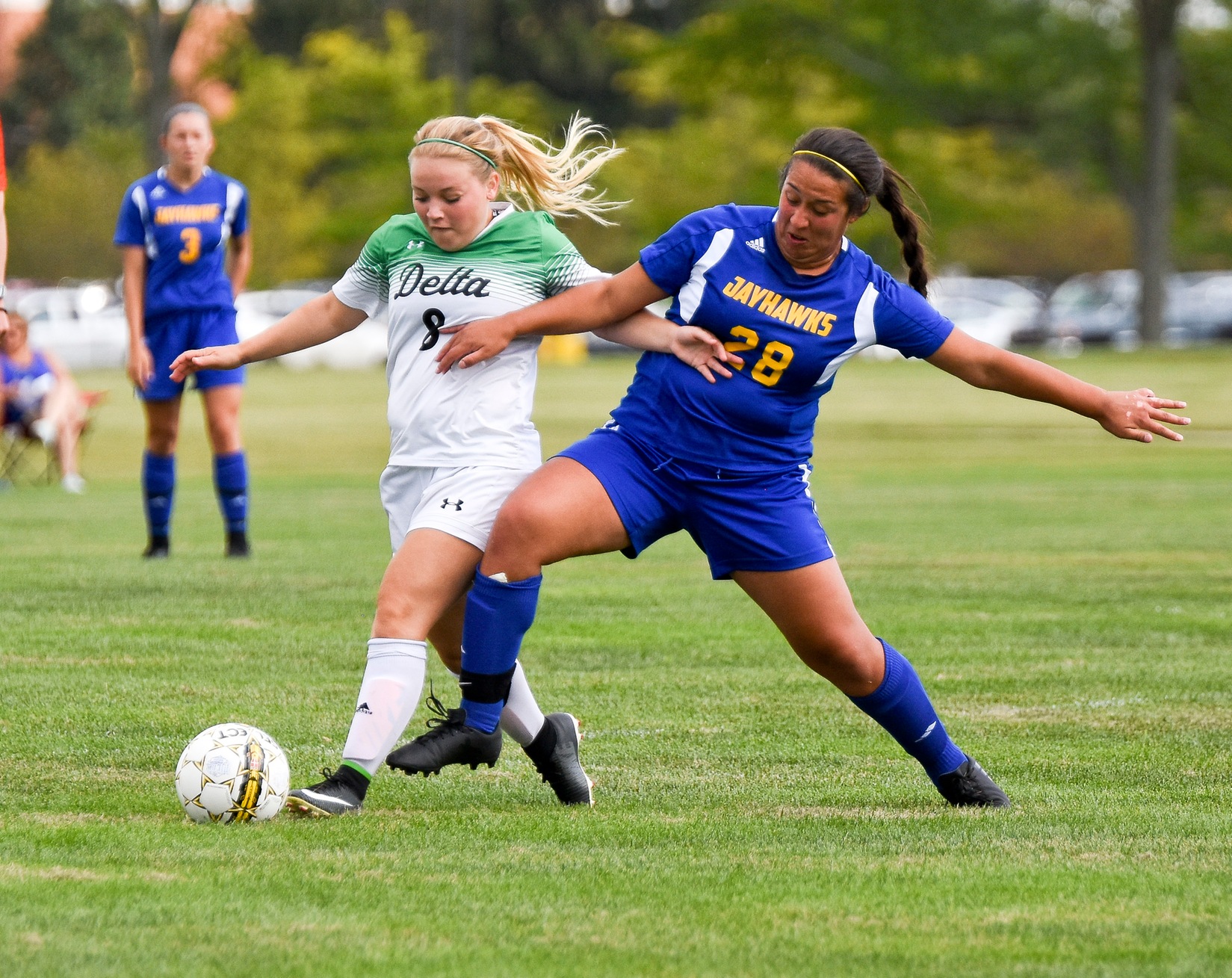 A Delta College player and a Muskegon CC player battle for the ball.